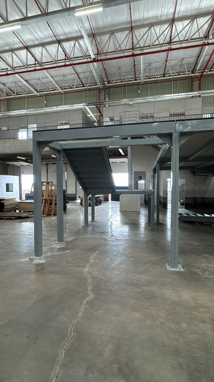 Detalhe de acabamento de escada e mezanino metálico em ambiente industrial.