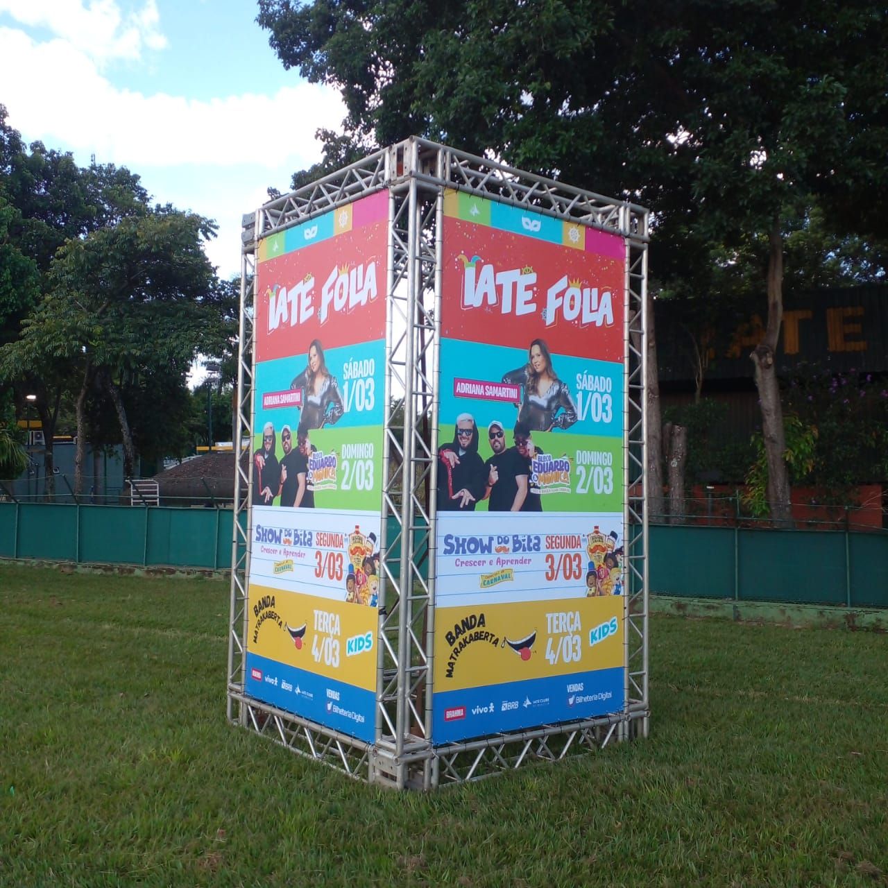 Estrutura de totem em treliça metálica revestida com painéis em lona para eventos externos.